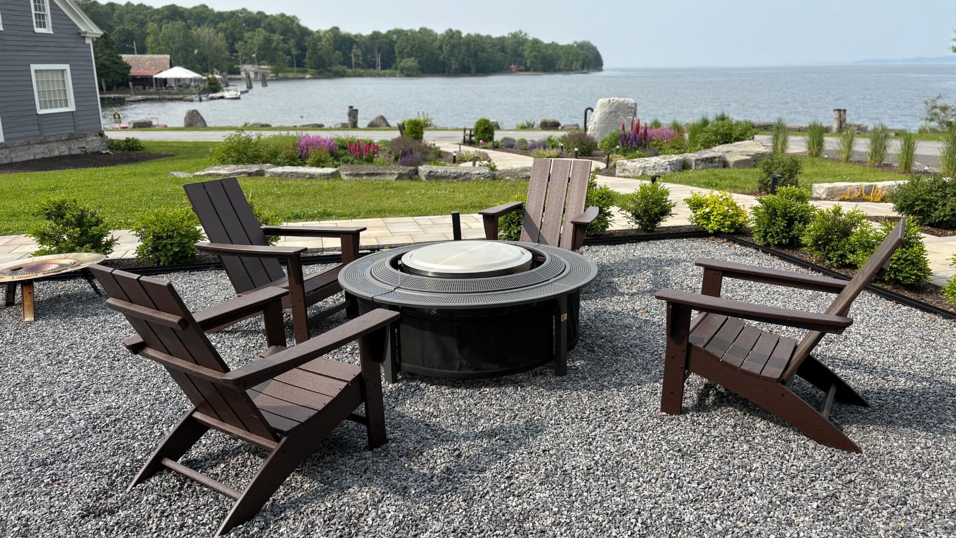 A cozy fire pit surrounded by wooden chairs, set against a lakeside backdrop.