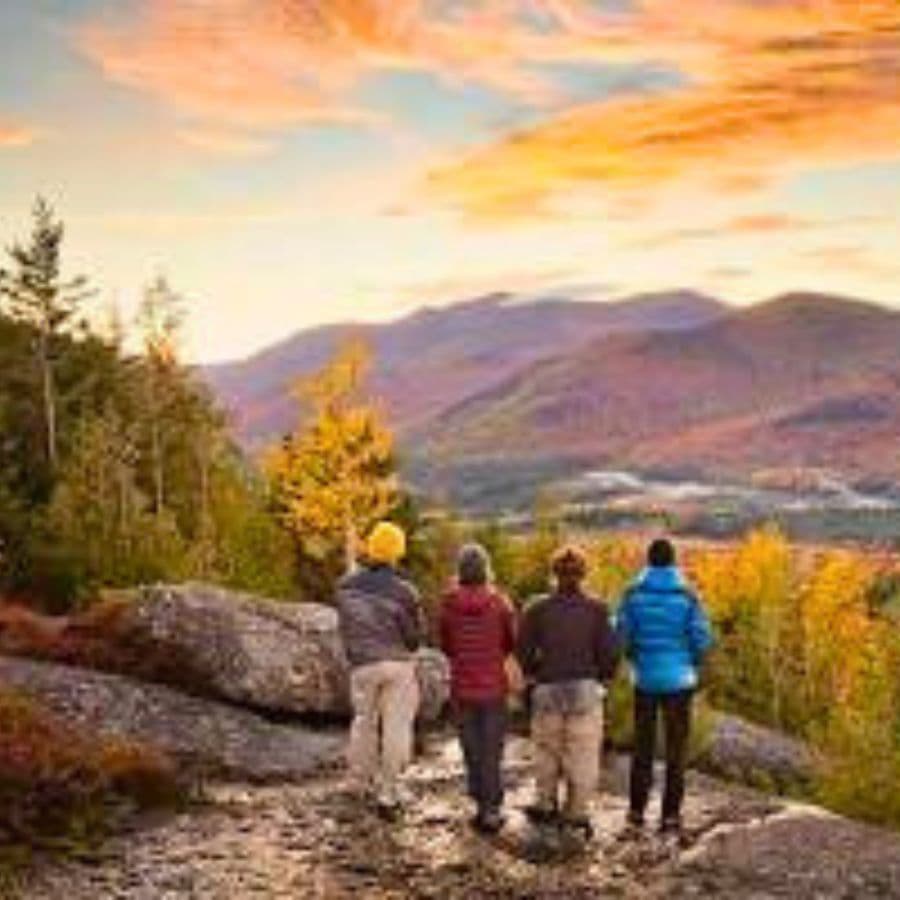Four hikers admire a vibrant sunset over a mountainous landscape.