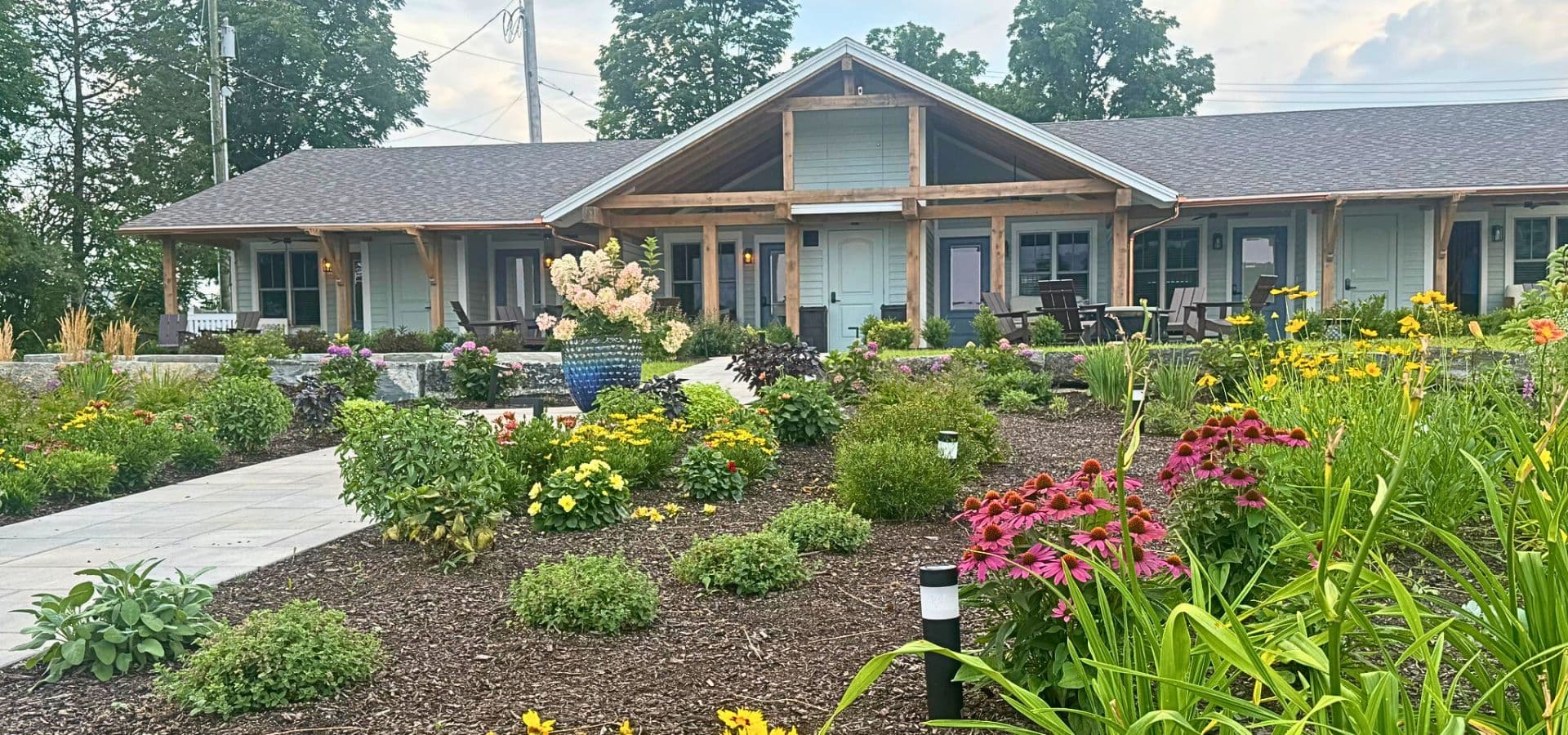 A charming building with a wooden porch surrounded by colorful gardens.