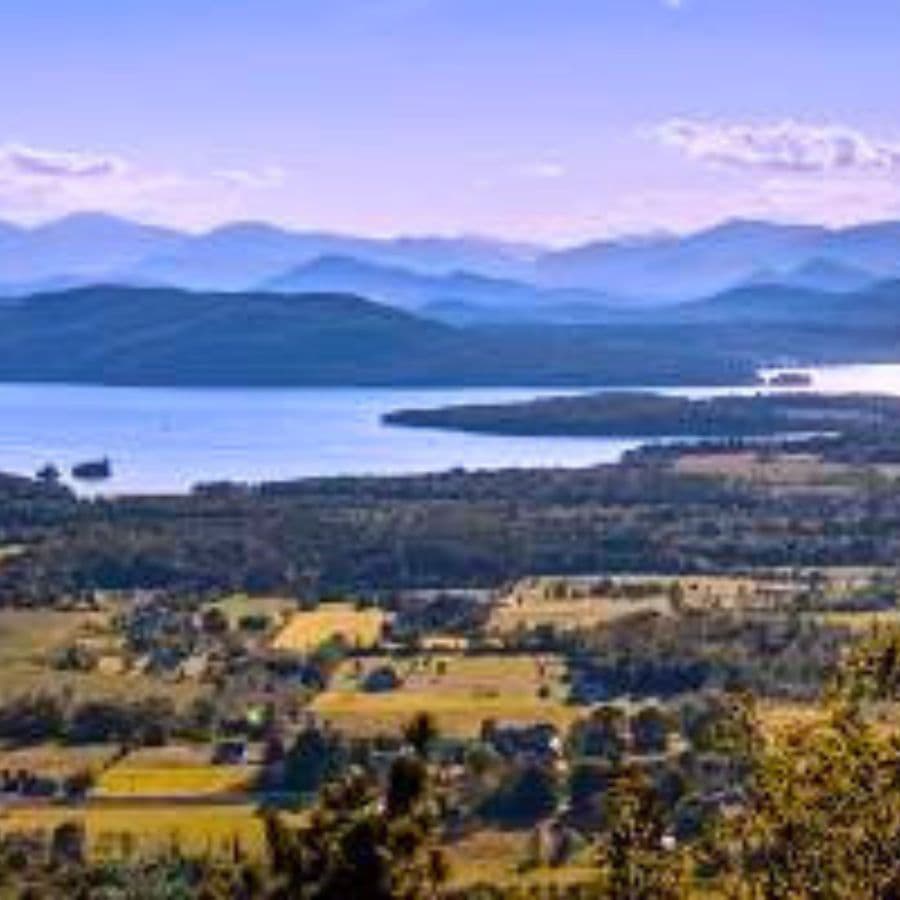 A panoramic view of rolling hills and a serene lake surrounded by distant mountains.