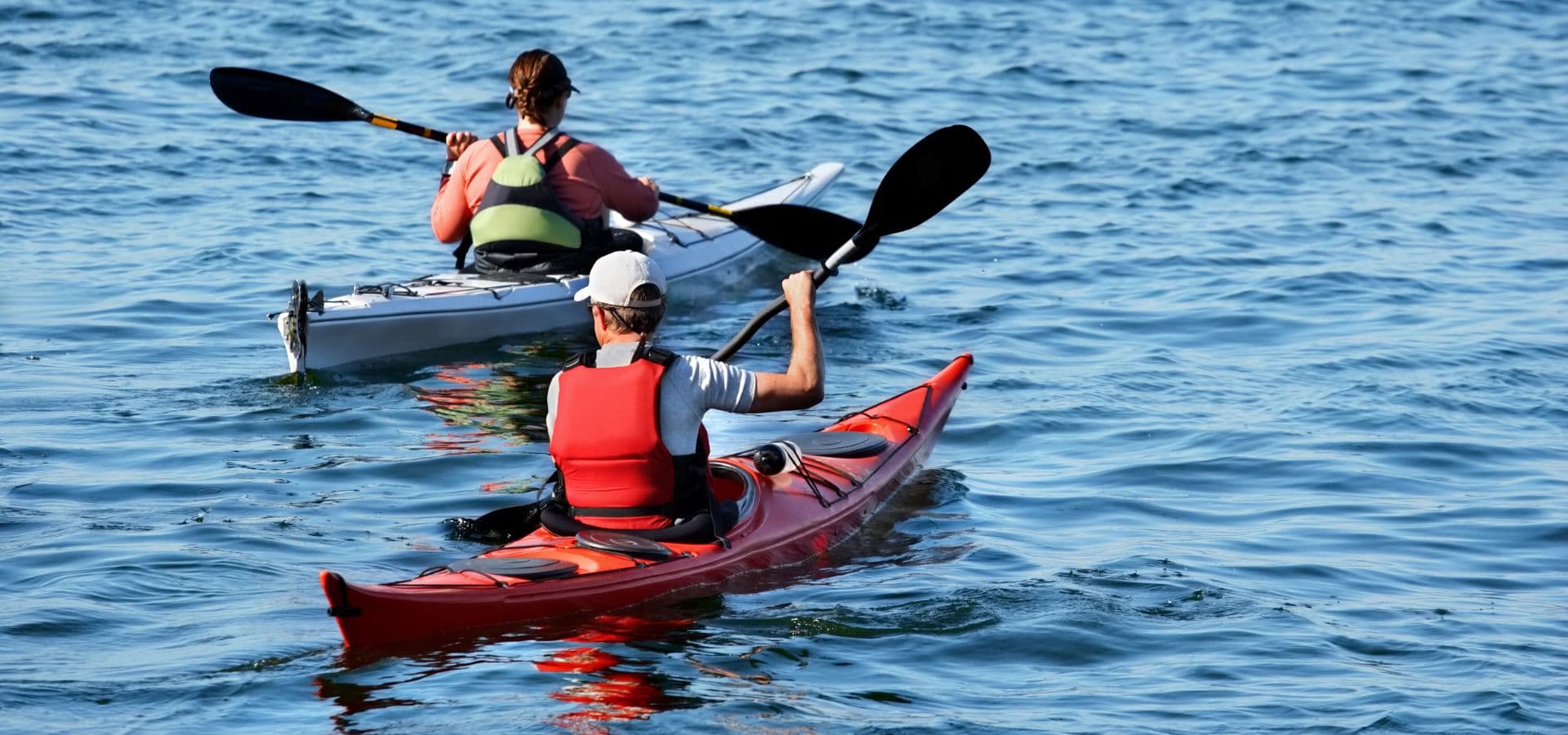 Two people kayaking side by side in the water.